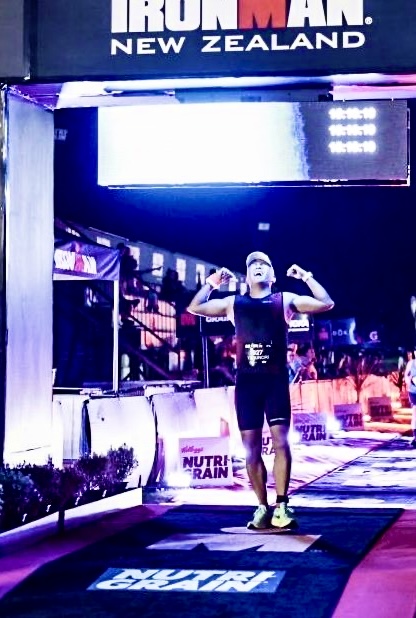 IRONMAN New Zealandのフィニッシュラインを両手を上げてゴールするセラピスト。